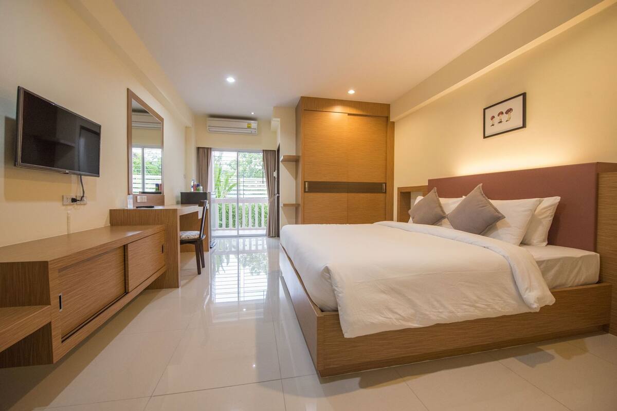 Une chambre d’hôtel avec un lit, une télévision, un bureau et un balcon.