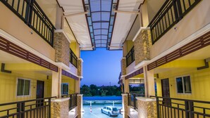 Un hotel de varios niveles con balcones, un paseo techado y una zona de estacionamiento.