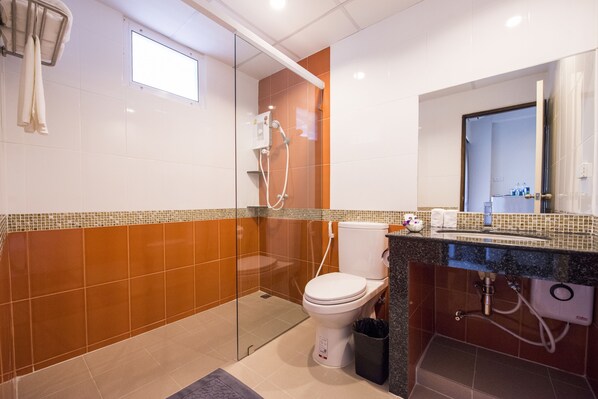 Un baño moderno con ducha envuelta en vidrio, inodoro blanco y encimera de granito con lavamanos.
