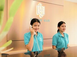 Two individuals in teal uniforms standing in front of a reception desk with a logo and the text "U DUAY SAM GARDEN HOUSE".
