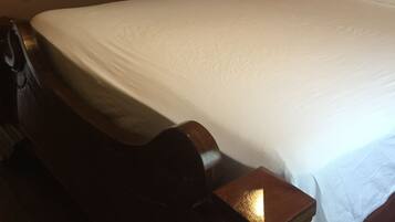 Une chambre d’hôtel avec un grand lit, une tête de lit en bois, une table de chevet avec une lampe et un miroir doté d’un cadre décoratif.