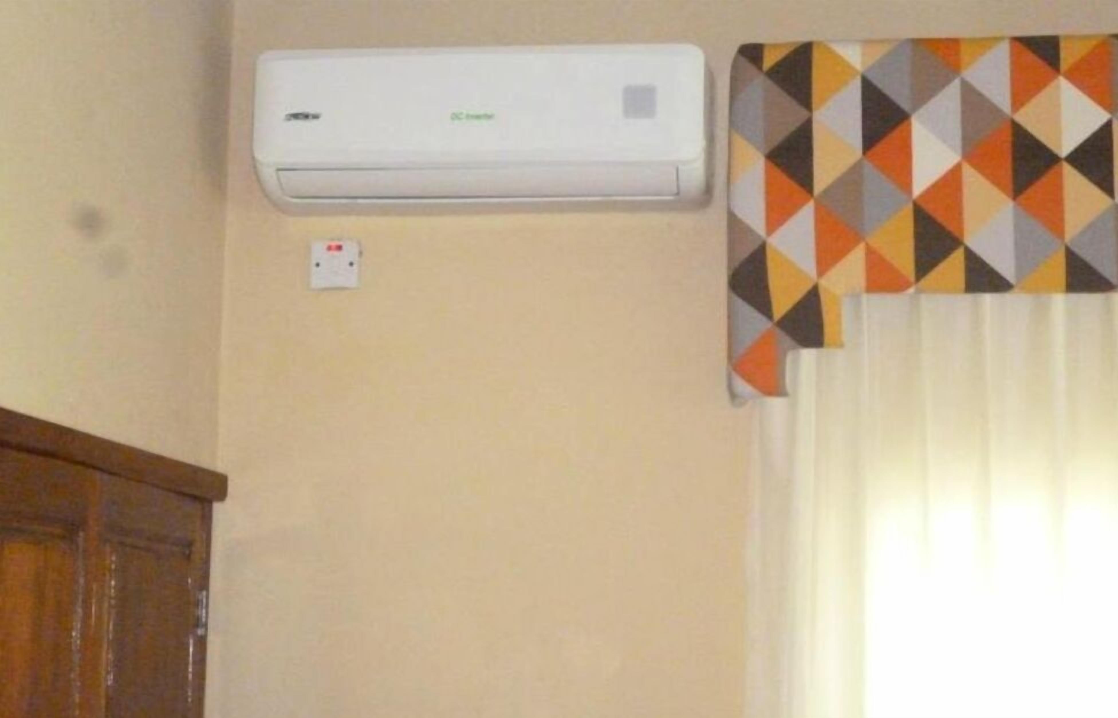Un aire acondicionado instalado en la pared, con un enchufe debajo.