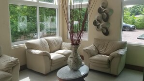 Una habitación con dos sofás color beige, una mesa de centro redonda y un jarrón decorativo.