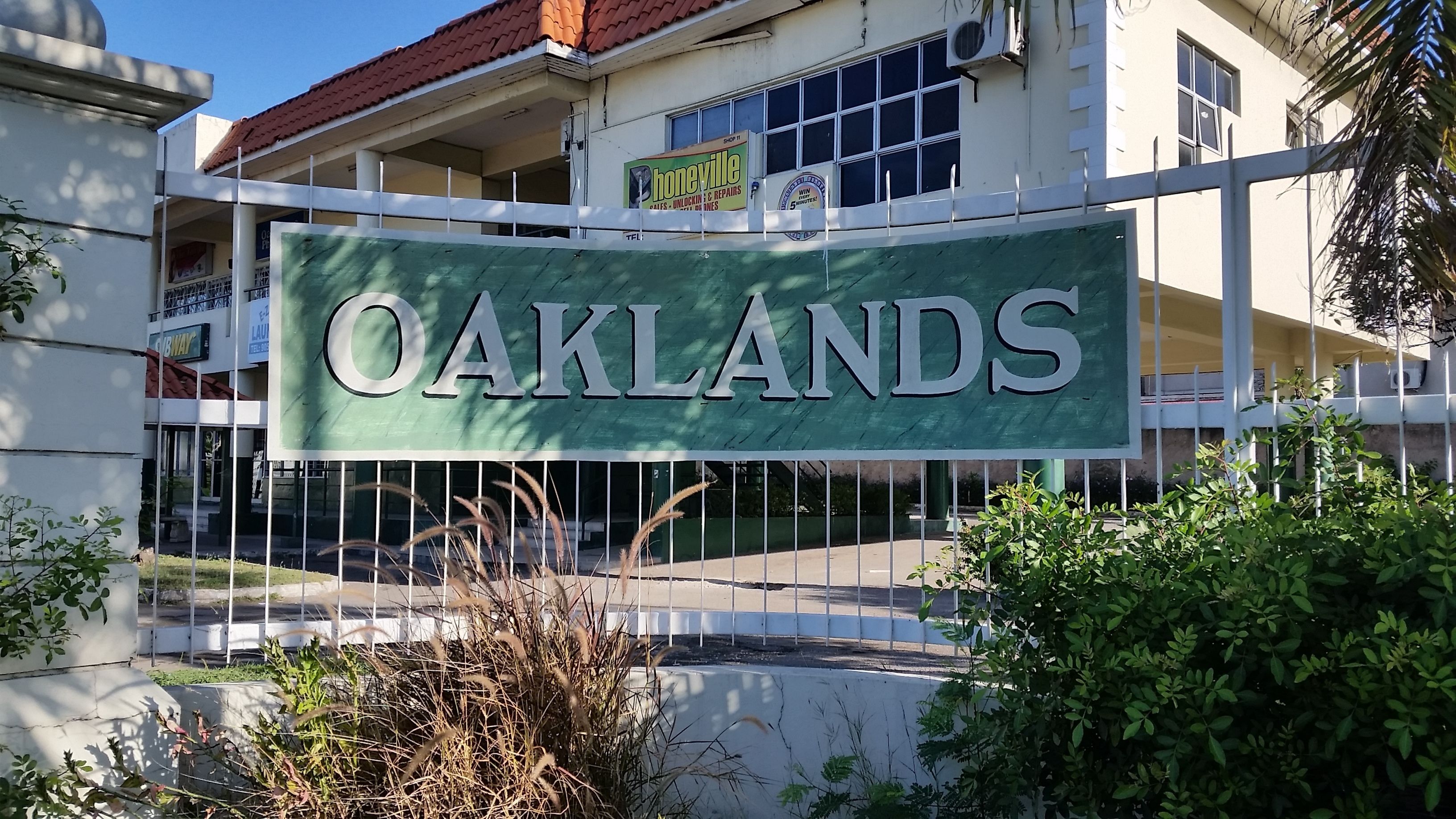 A sign for "Oaklands" with a white fence and greenery in the foreground.