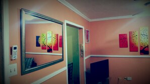 A room with a large mirror, a door, and several wall-mounted paintings.