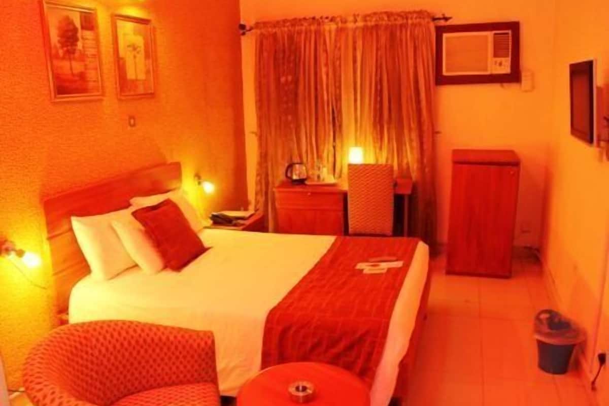 A hotel room with a bed, a chair, a desk, a television, and a cabinet.