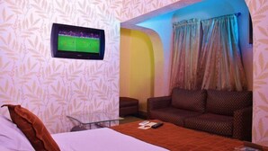 A hotel room with a bed, a TV mounted on the wall, a sofa, and a curtain. - Vines Hotel (Abuja)