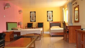A hotel room with two single beds, a desk, a chair, a small table, and a sofa. - Golden Gate Hotel Abuja (Abuja)