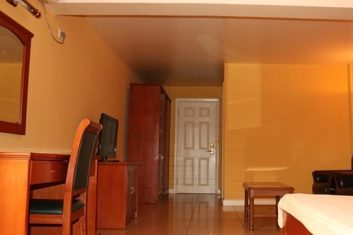 A hotel room with a bed, a desk, a chair, a television, and a door.