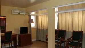 A room with a TV, wooden furniture, and curtains. - Golden Gate Hotel Abuja (Abuja)