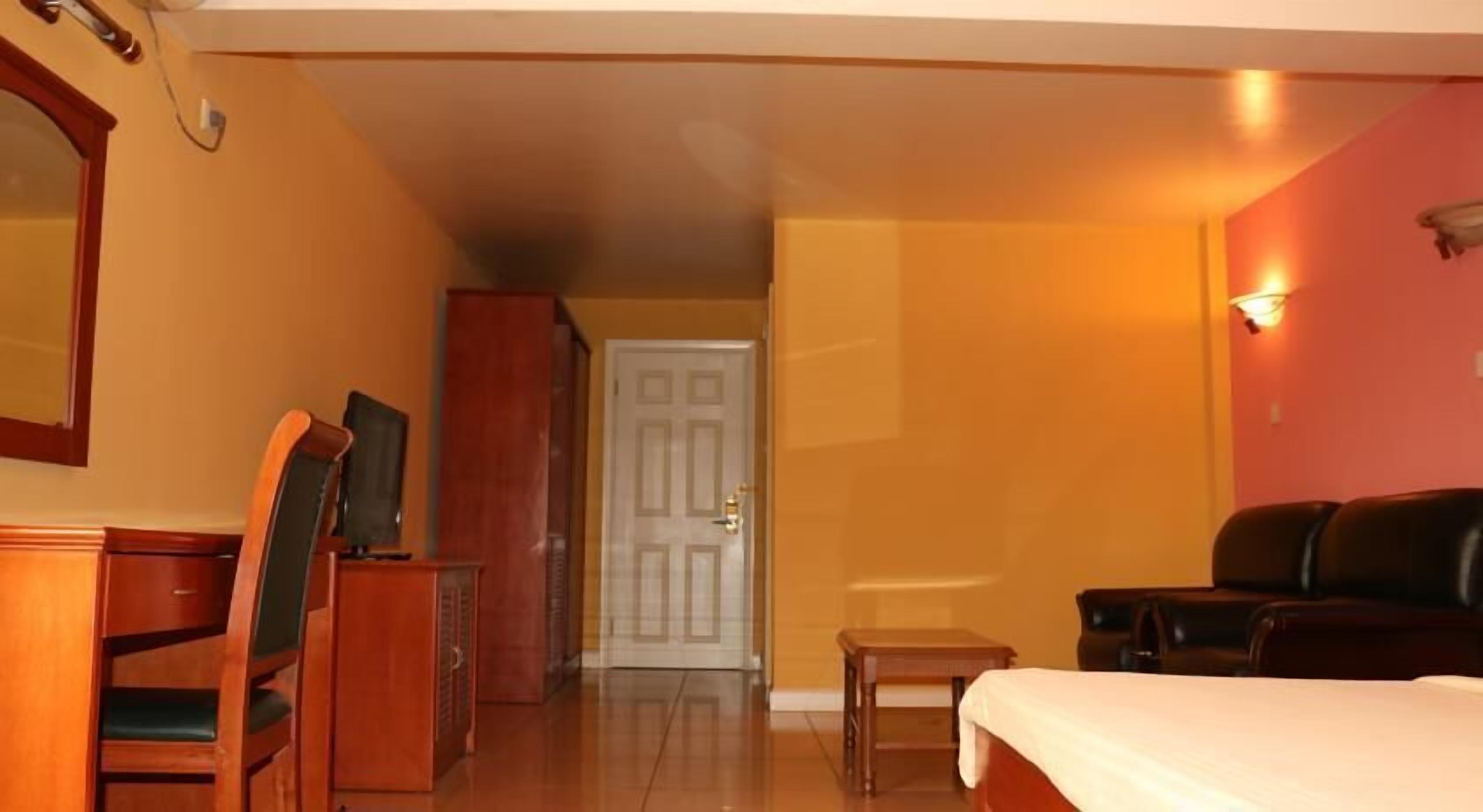 Ein Hotelzimmer mit Bett, Schreibtisch, Stuhl, Fernseher und Kleiderschrank.