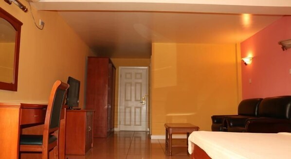 A hotel room with a bed, a desk, a chair, a television, and a wardrobe.
