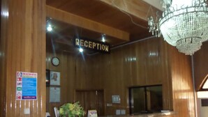 A reception area with a wooden reception desk, a chandelier, and a statue of a woman. - Parkview Hotel Abuja (Abuja)