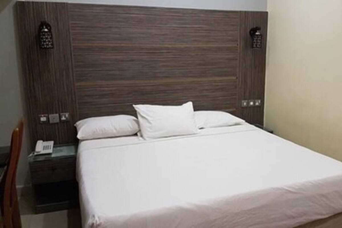 A neatly made bed with white linens in a hotel room.