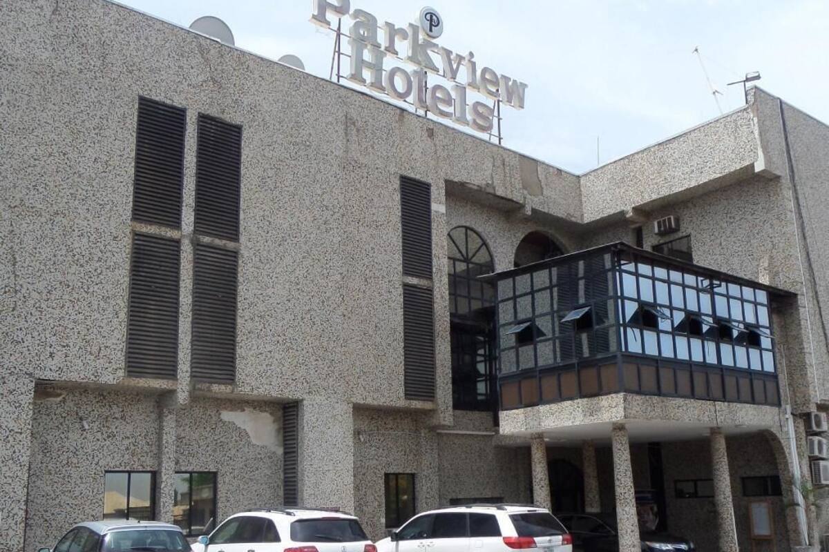 A building with a sign for Parkview Hotels, featuring a textured facade, large windows, and a balcony area.