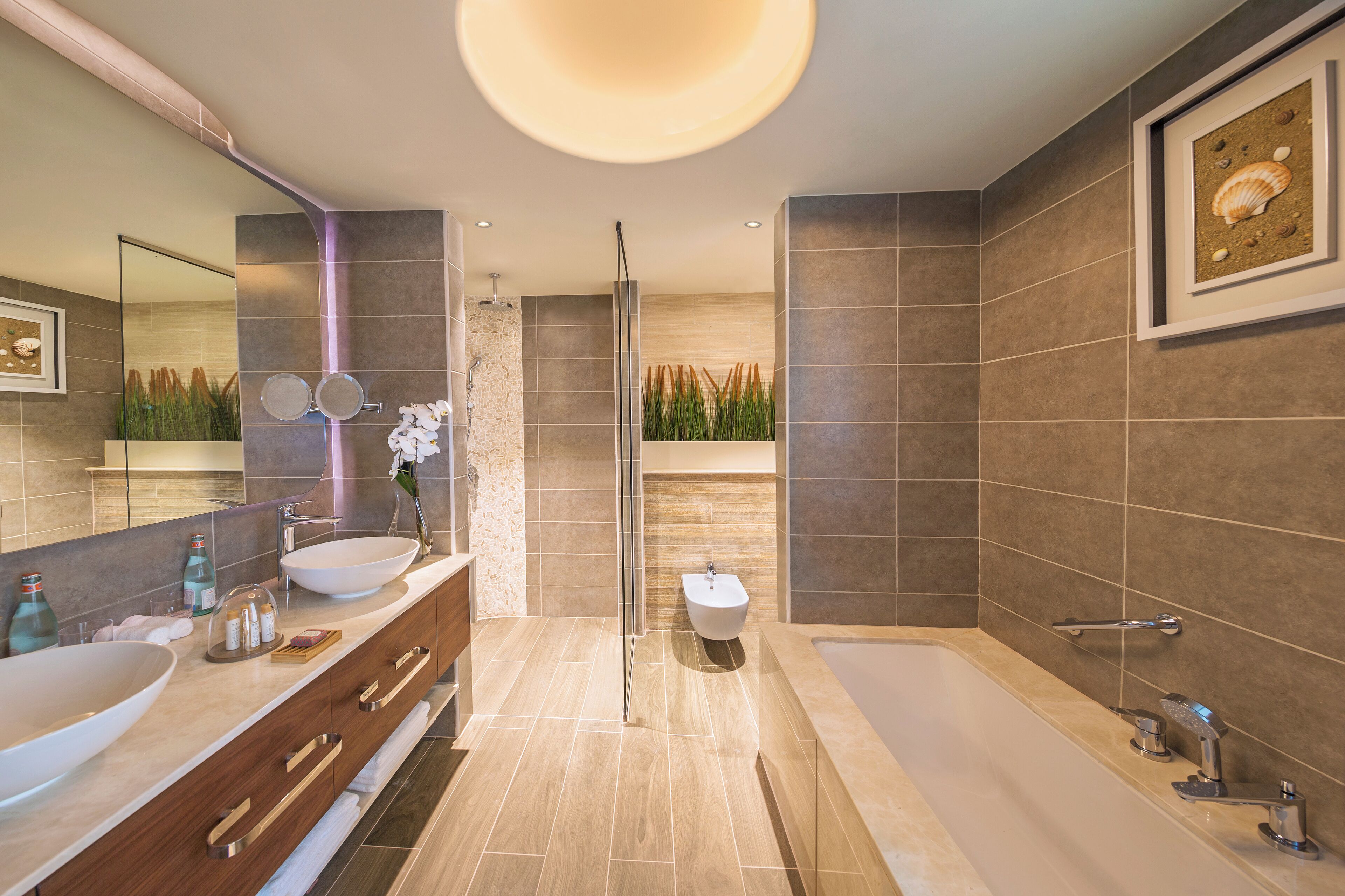 Un baño moderno con una bañera grande, una zona de ducha separada y un lavabo con un mueble amplio y varios cajones.
