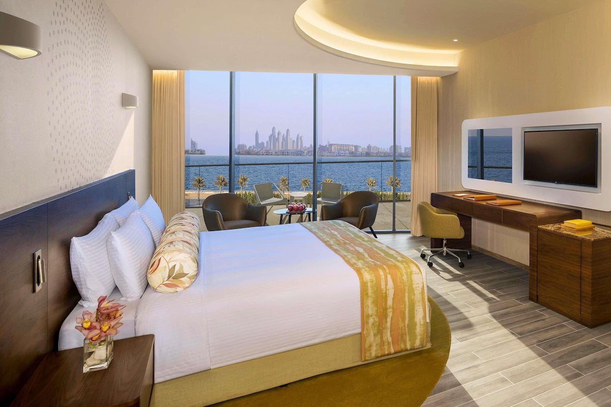 Ein Hotelzimmer mit Bett, Schreibtisch, Fernseher und Blick auf die Stadtlandschaft.