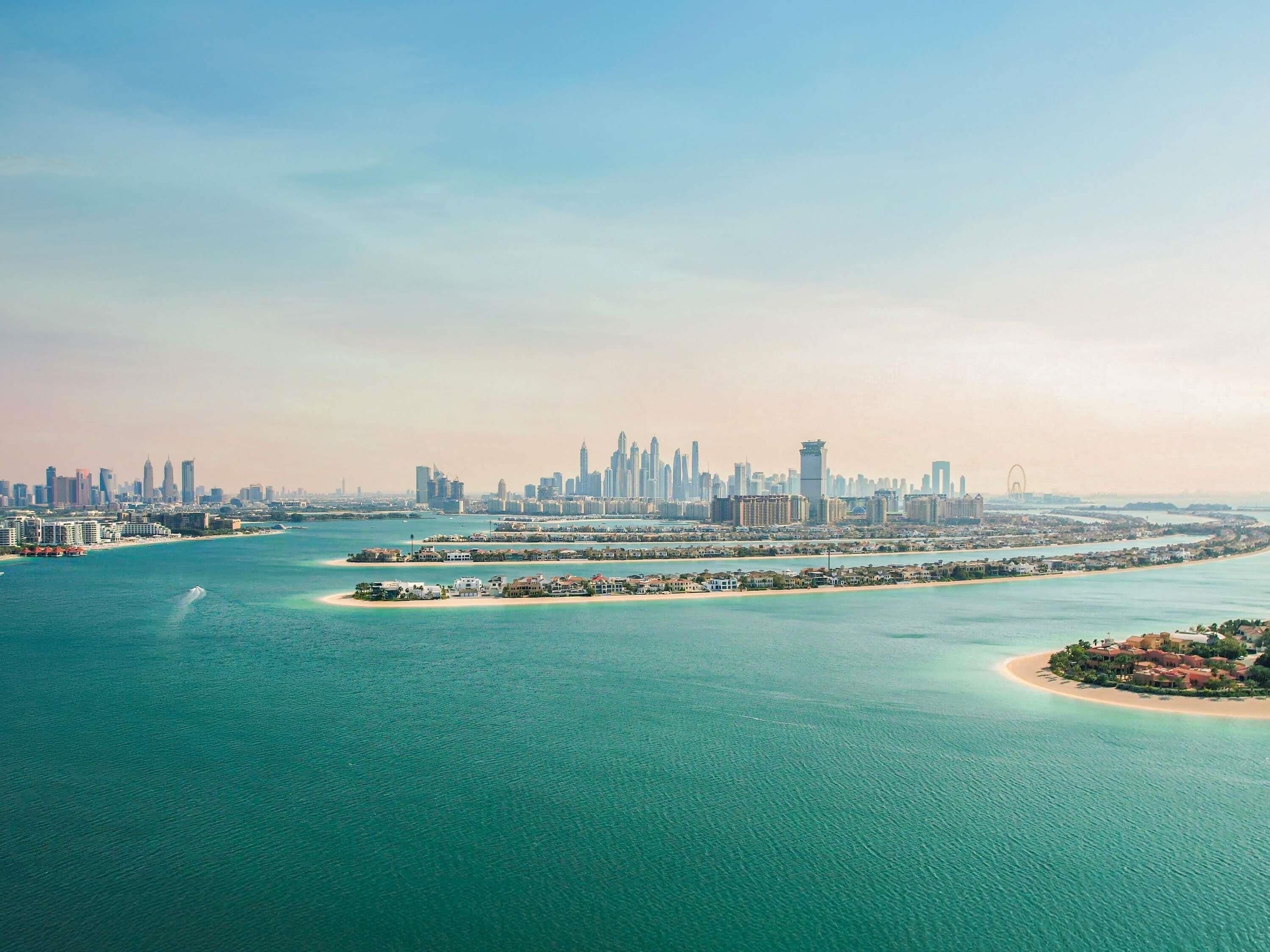 A coastal cityscape with a prominent skyline, a marina, and a large body of water.