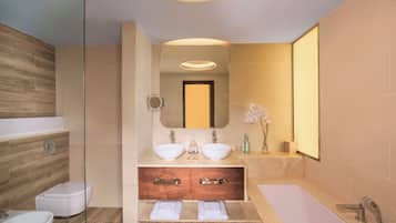 A modern bathroom with two sinks, a bathtub, and a toilet.