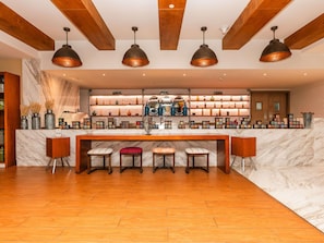 Une cuisine moderne avec des plans de travail en marbre, des tabourets de bar en bois et des luminaires suspendus.