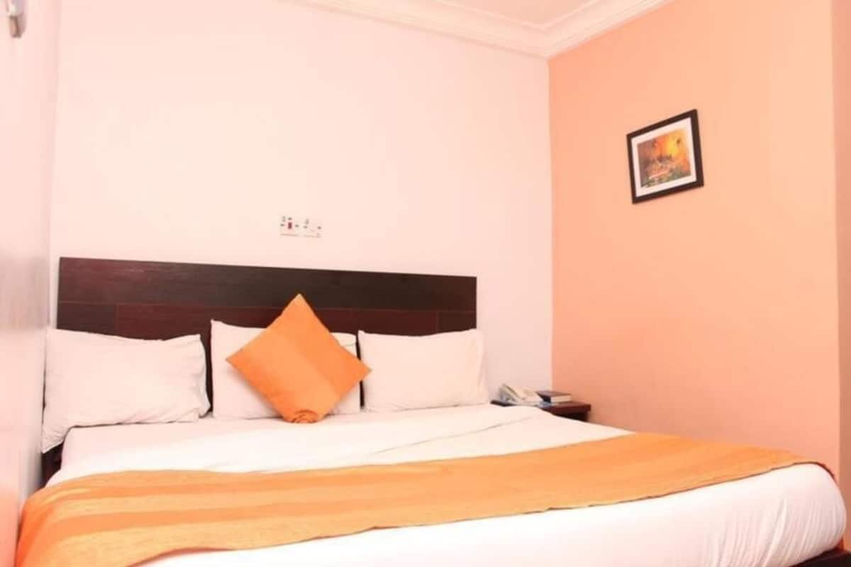 Una habitación de hotel con una cama, una mesita de noche y un cuadro en la pared.