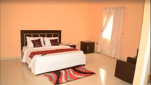 A bedroom with a bed, nightstand, and a small cabinet. - Chariot Hotel (Abuja)