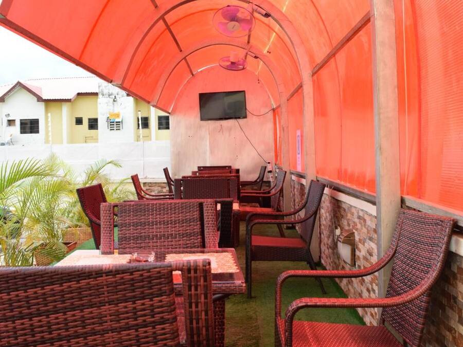 An indoor dining area with wicker furniture and a TV screen on the wall.