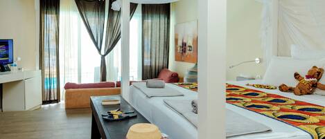 A hotel room with a bed, a desk, a sofa, and a dining table.