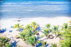 Una playa con palmeras, agua azul cristalina y algunas personas.