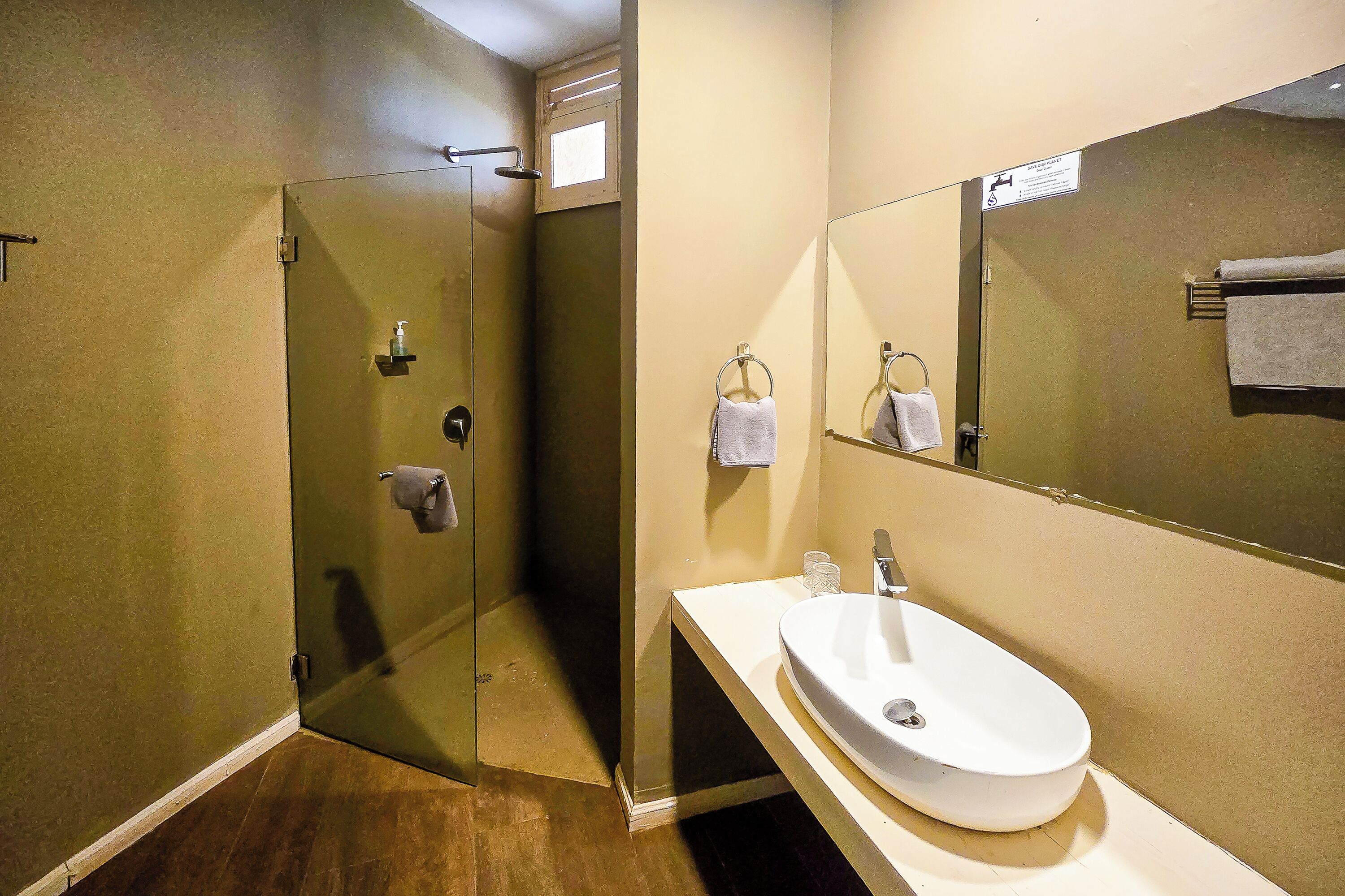 A bathroom with a glass-enclosed shower, a sink with a mirror, and a towel rack.