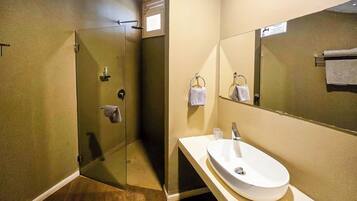 A bathroom with a glass-enclosed shower, a sink with a mirror, and a towel rack.