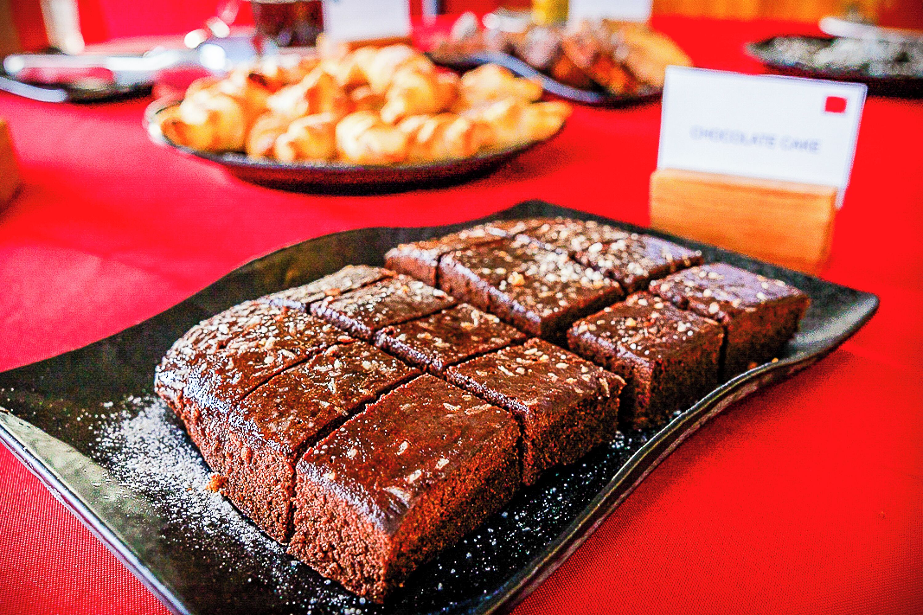 A tray of brownies on a red tablecloth.