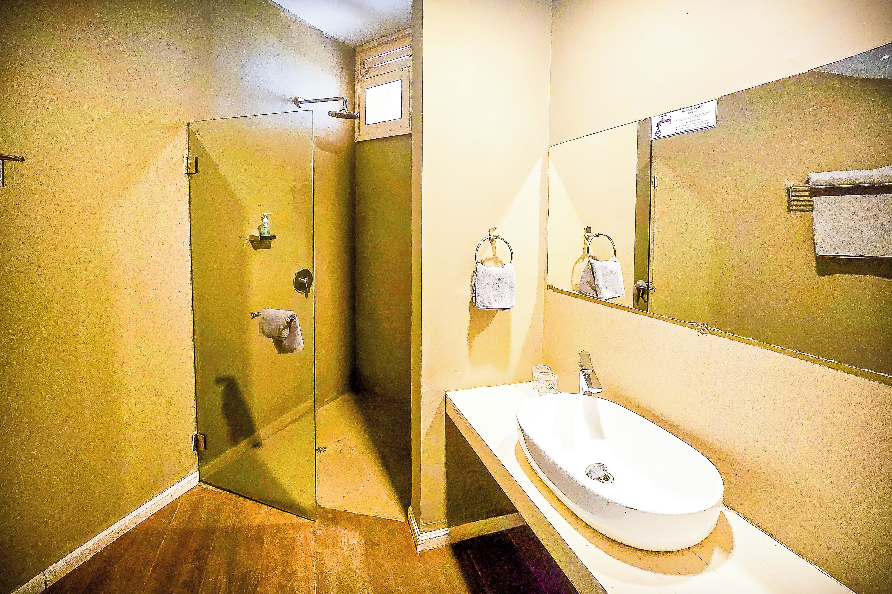 Een badkamer met een douche met glazen wand, een wastafel en een spiegel.