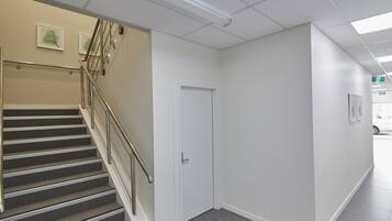 Un interior limpio y moderno con una escalera, una puerta blanca y un pasillo que conduce a una salida.