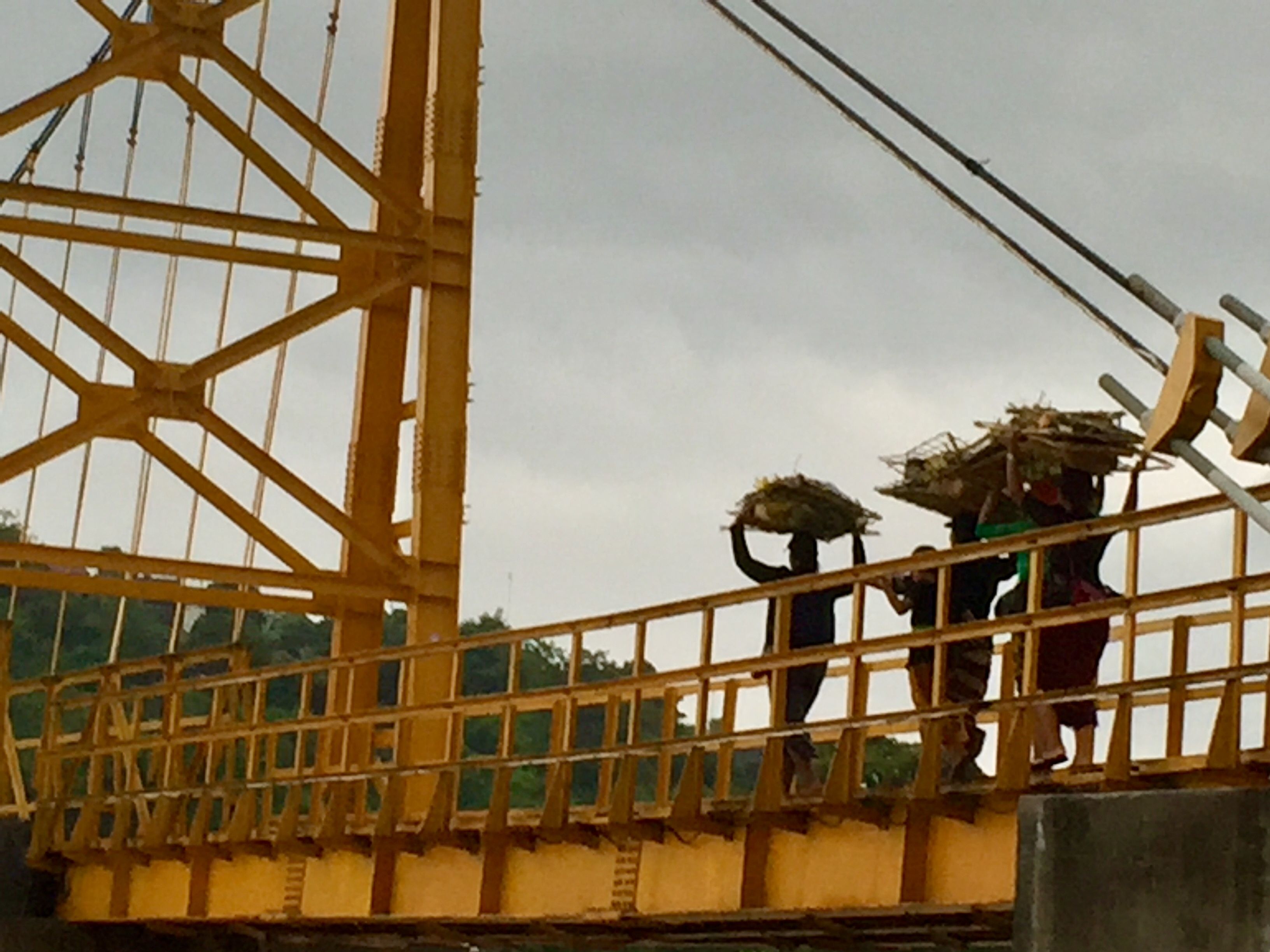 Un puente peatonal con estructura de celosía metálica y barandilla amarilla.