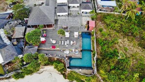 An aerial view of a resort with a central pool, multiple buildings, and surrounding greenery. - The Palms Ceningan Hotel (Ceningan Island)