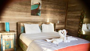A wooden room with a bed, a nightstand, and a wall painting. - The Palms Ceningan Hotel (Ceningan Island)