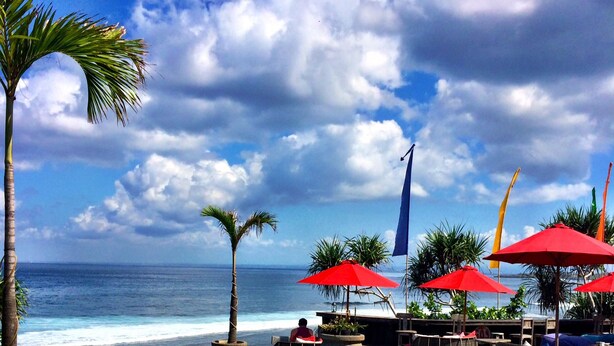 A poolside area with lounge chairs and umbrellas, overlooking the ocean. - The Palms Ceningan Hotel (Ceningan Island)