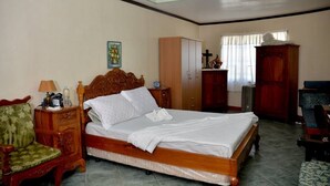Un dormitorio con una cama de madera, una mesita de noche, una silla, un armario y una ventana con cortinas.