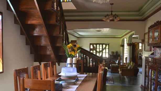 Un área de comedor con una escalera de madera, un candelabro y una mesa de comedor con sillas.