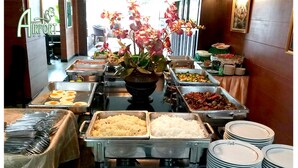 Un buffet proposant une variété de plats et agrémenté d’un arrangement floral en guise de décoration centrale.