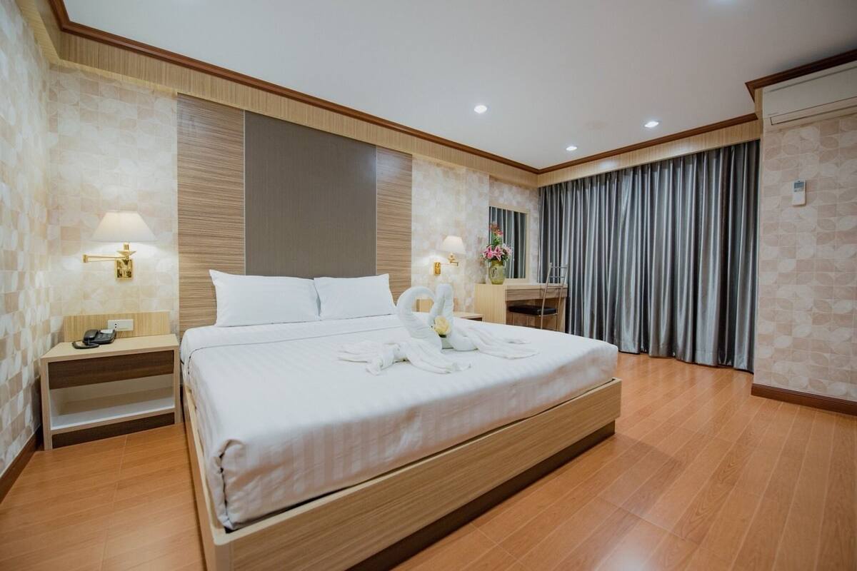 Quarto de hotel com uma cama grande, mesas de cabeceira com luminárias, uma escrivaninha e uma cadeira.