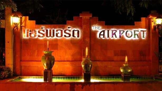 Une enseigne portant l’inscription « The Airport », flanquée de deux vases placés sur une étagère carrelée.
