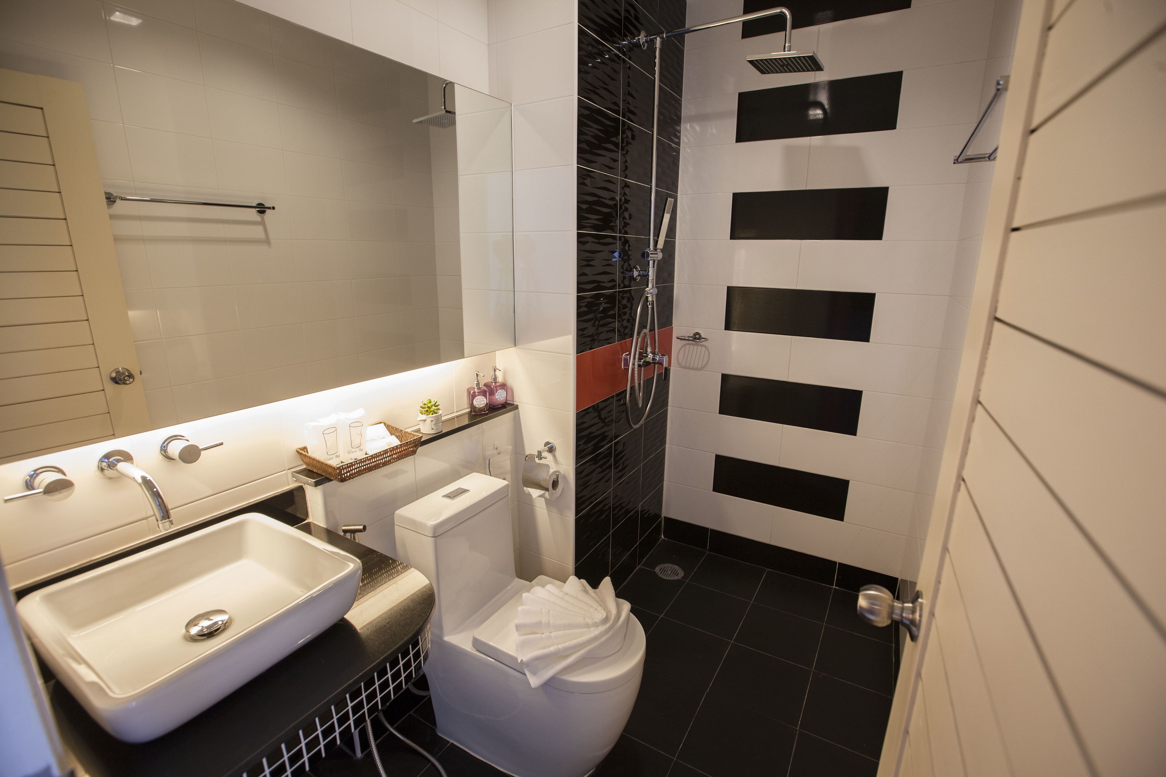 A modern bathroom with a white sink, toilet, and shower.