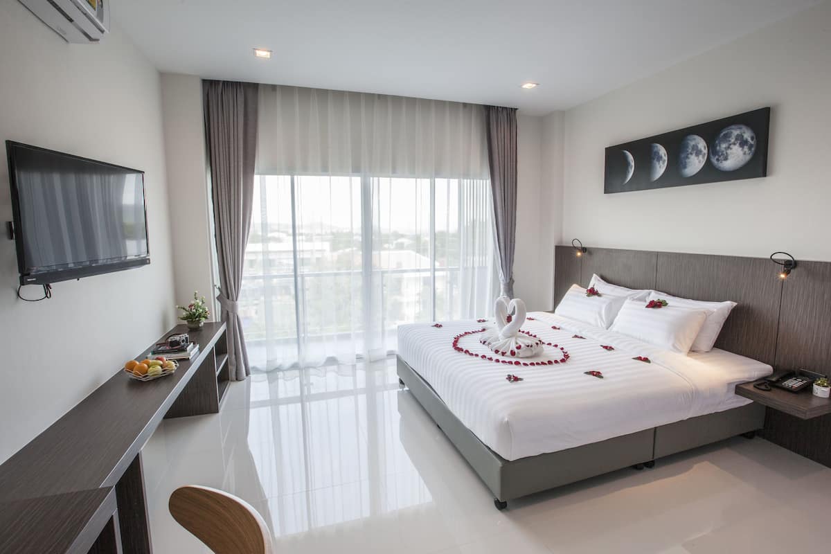 A hotel room with a bed, a desk, a TV, and a window with curtains.