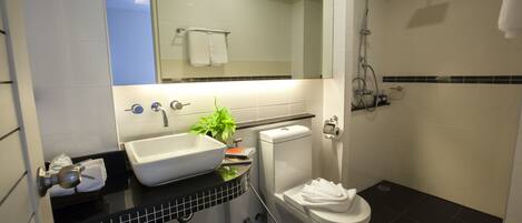 A modern bathroom with a white sink, toilet, and shower.
