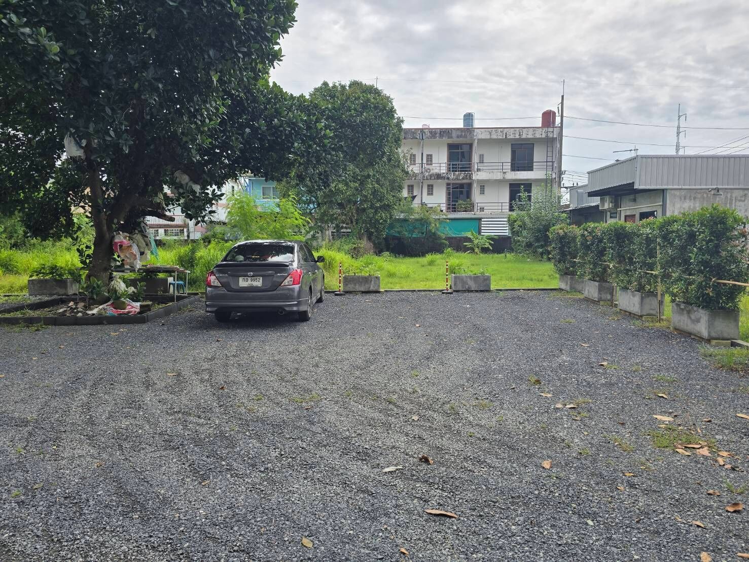 A gravel driveway leading to a building with a white facade and multiple windows.