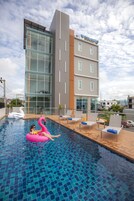 Un hotel moderno con piscina, sillas de descanso y un flotador con forma de cisne.
