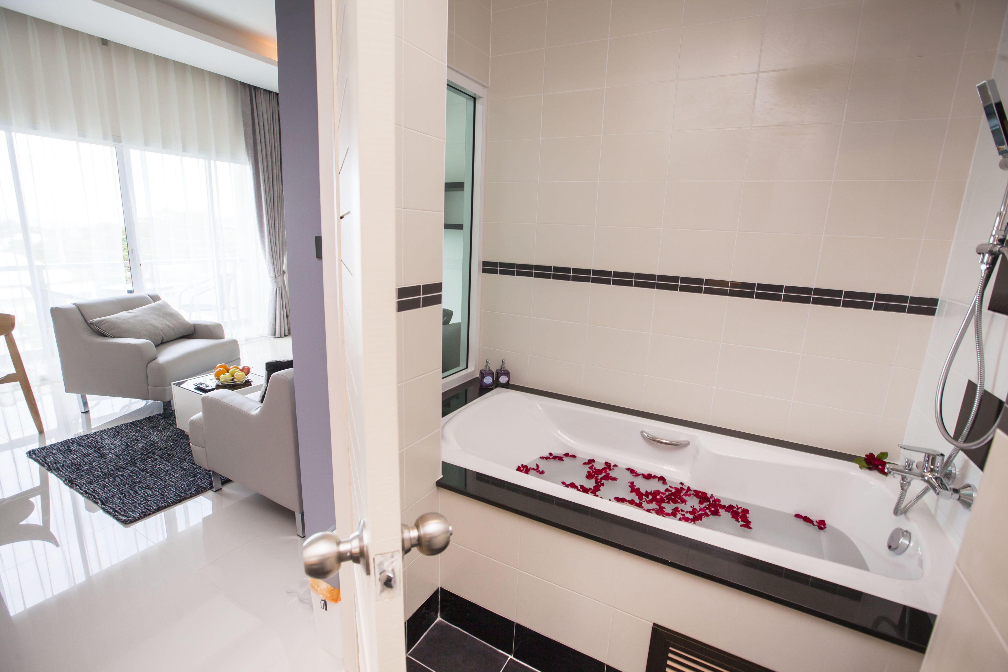 A modern bathroom with a bathtub, shower, and a seating area with a sofa and coffee table.