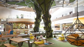 A modern indoor space with a central tree, seating areas, and a bar. - Hue Hotels and Resorts Boracay Managed by HII (Boracay Island)